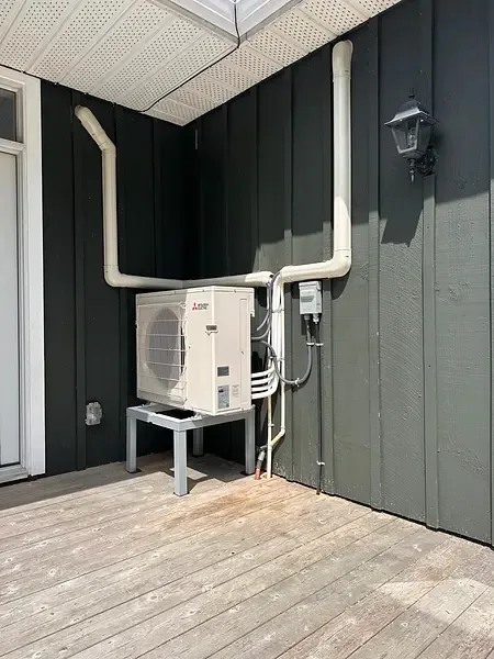 Real Burt's Breeze installation — ductless heat pump neatly mounted beside a cottage deck