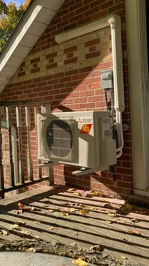 Mini-split condenser neatly wall-mounted on brick by Burt's Breeze